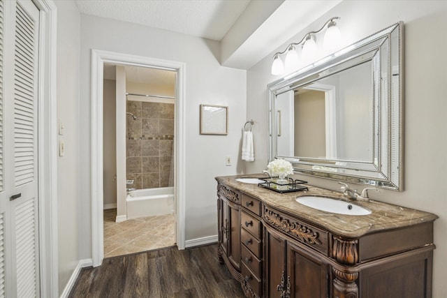 bathroom featuring hardwood / wood-style flooring, tiled shower / bath, vanity, and a textured ceiling