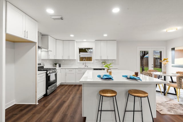 kitchen featuring a kitchen island, a breakfast bar, sink, white cabinets, and gas stove