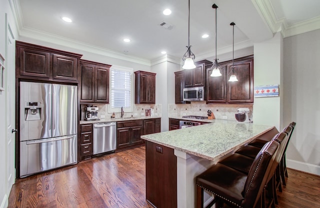 kitchen with sink, hanging light fixtures, a kitchen breakfast bar, kitchen peninsula, and stainless steel appliances