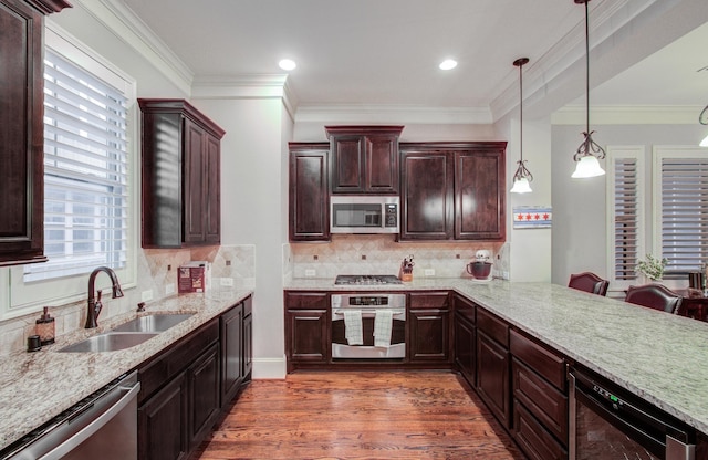 kitchen featuring sink, hanging light fixtures, appliances with stainless steel finishes, dark hardwood / wood-style flooring, and kitchen peninsula