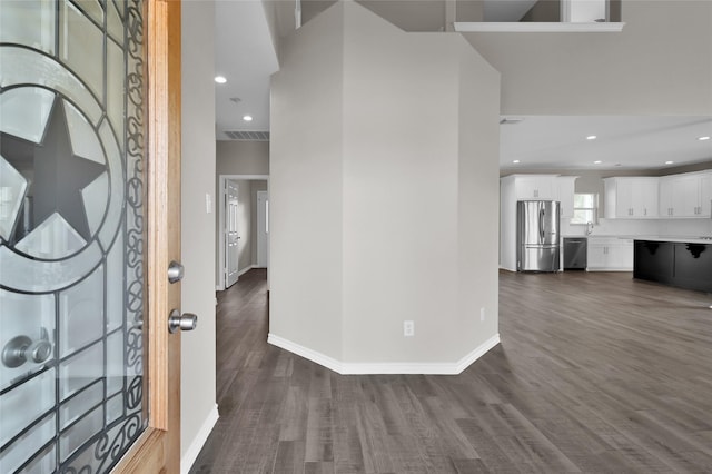 entryway featuring sink, a towering ceiling, and dark wood-type flooring