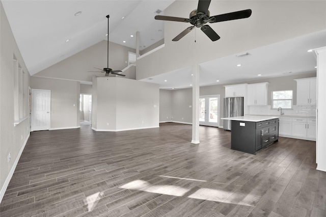 unfurnished living room featuring high vaulted ceiling, sink, hardwood / wood-style flooring, ceiling fan, and french doors