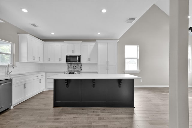 kitchen with sink, stainless steel appliances, a center island, and white cabinets