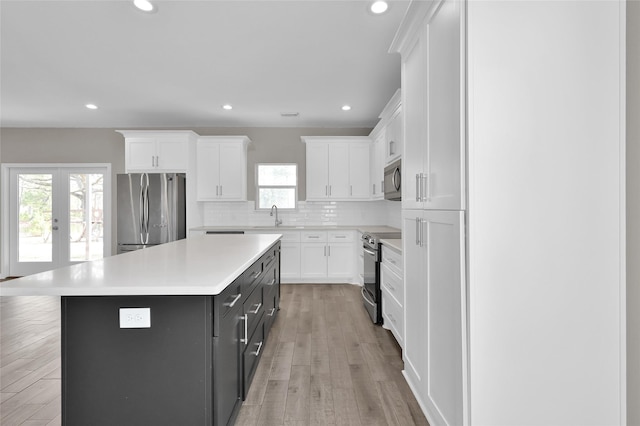 kitchen with a kitchen island, sink, white cabinets, stainless steel appliances, and french doors