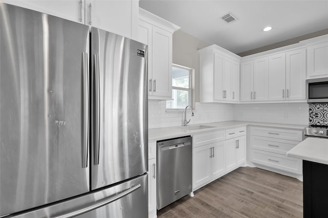 kitchen featuring stainless steel appliances, white cabinetry, sink, and tasteful backsplash