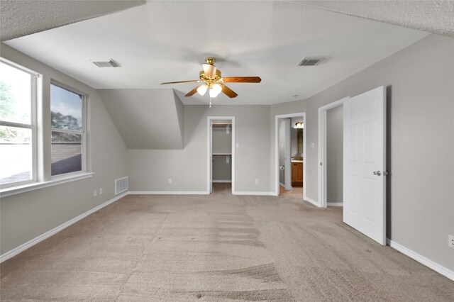 bonus room with ceiling fan, vaulted ceiling, and light carpet