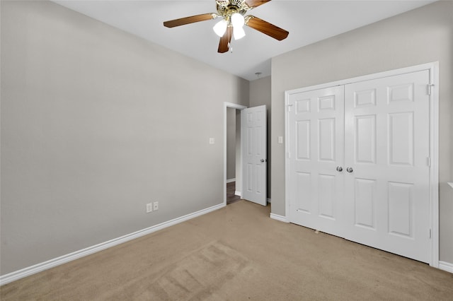 unfurnished bedroom featuring ceiling fan, light colored carpet, and a closet