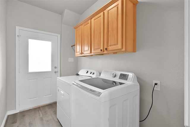 laundry area with washer and clothes dryer, cabinets, and light wood-type flooring