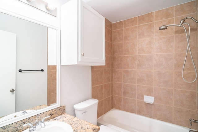 full bathroom featuring tiled shower / bath, vanity, and toilet