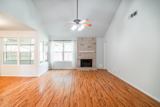 unfurnished living room with ceiling fan, a brick fireplace, high vaulted ceiling, and light hardwood / wood-style flooring