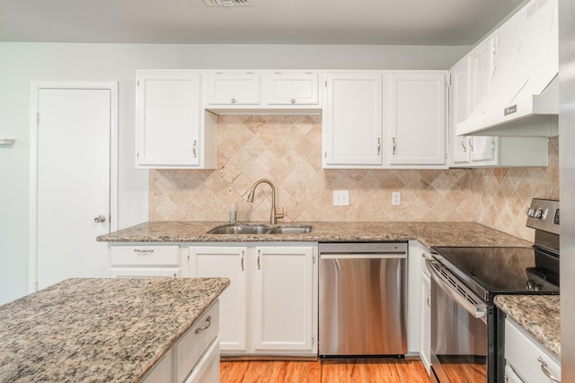 kitchen with appliances with stainless steel finishes, sink, white cabinets, and light stone counters