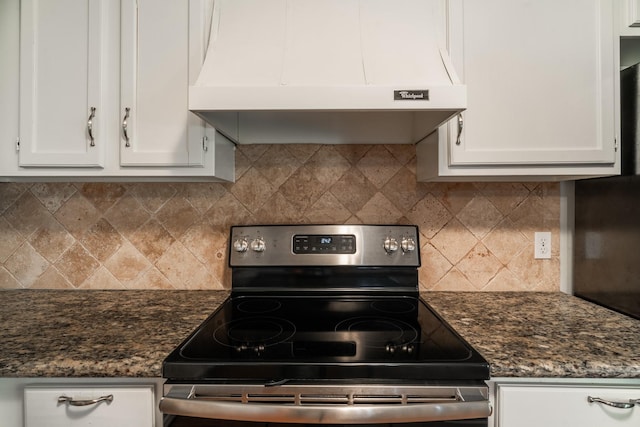 kitchen with white cabinetry, stainless steel range with electric cooktop, dark stone counters, and wall chimney exhaust hood