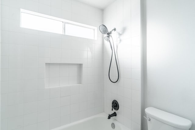 bathroom featuring tiled shower / bath and toilet