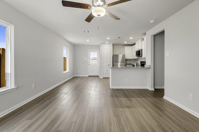 unfurnished living room with recessed lighting, visible vents, a ceiling fan, wood finished floors, and baseboards