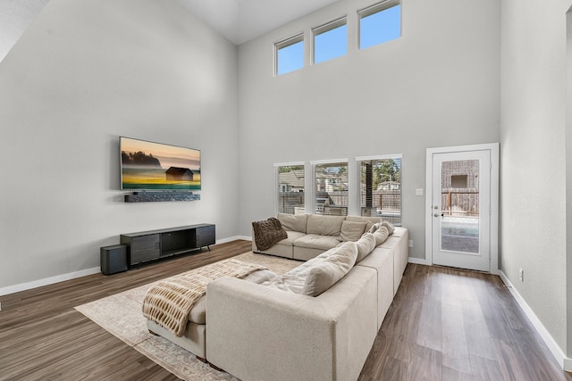 living room with a wealth of natural light, dark wood-type flooring, and a high ceiling