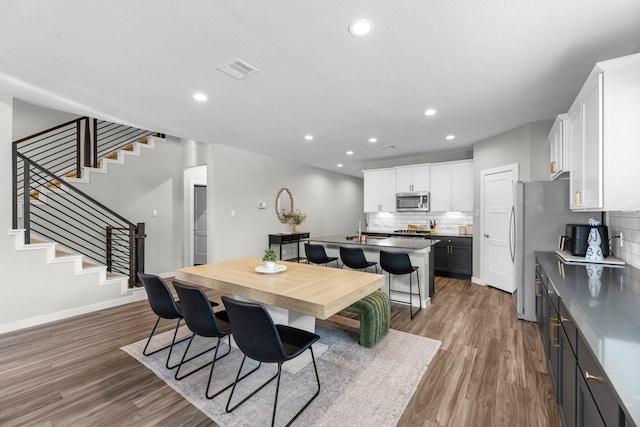 dining room with stairway, recessed lighting, wood finished floors, and visible vents