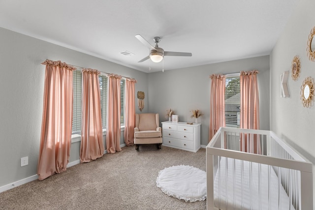 bedroom with a nursery area, light colored carpet, and ceiling fan