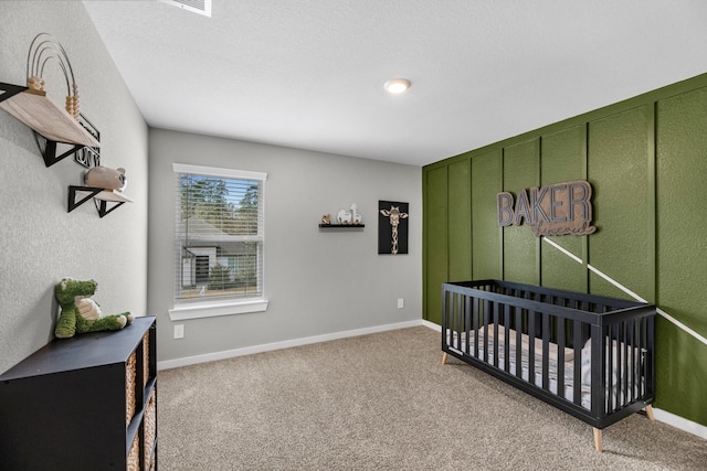 bedroom with a nursery area, baseboards, and carpet floors