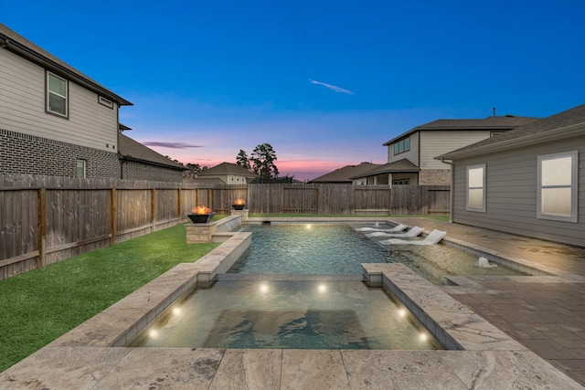 pool at dusk with a patio area, pool water feature, and an in ground hot tub