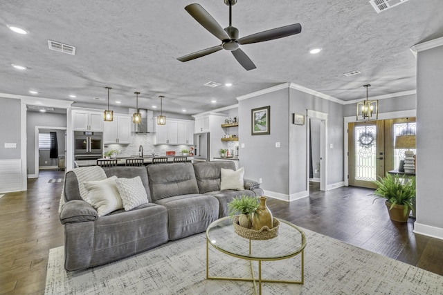 living room featuring ornamental molding, dark hardwood / wood-style floors, sink, and a textured ceiling