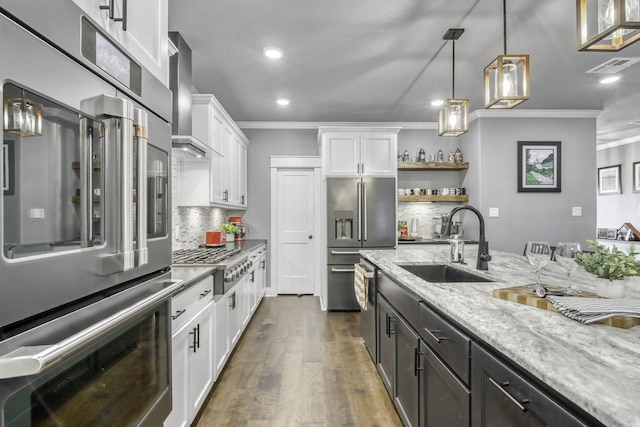 kitchen featuring pendant lighting, sink, wall chimney range hood, appliances with stainless steel finishes, and white cabinets