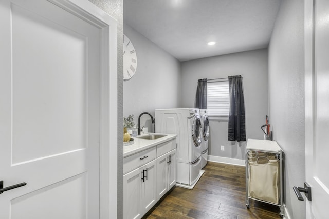 laundry room featuring cabinets, sink, washing machine and clothes dryer, and dark hardwood / wood-style flooring