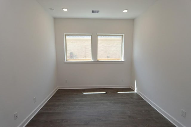 unfurnished room featuring visible vents, baseboards, and dark wood finished floors