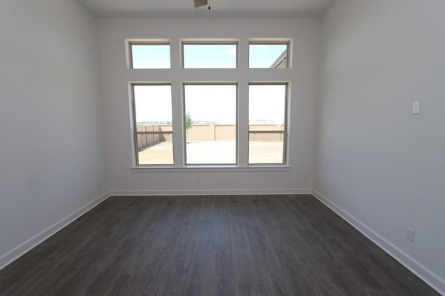 spare room featuring dark wood-style flooring and baseboards