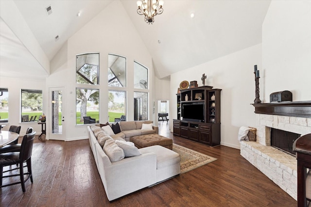 living room with high vaulted ceiling, a stone fireplace, an inviting chandelier, and dark hardwood / wood-style flooring