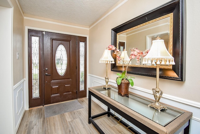 entryway with ornamental molding, a textured ceiling, and light wood-type flooring