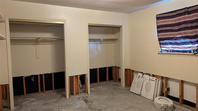 unfurnished bedroom with multiple closets, concrete floors, and a textured ceiling