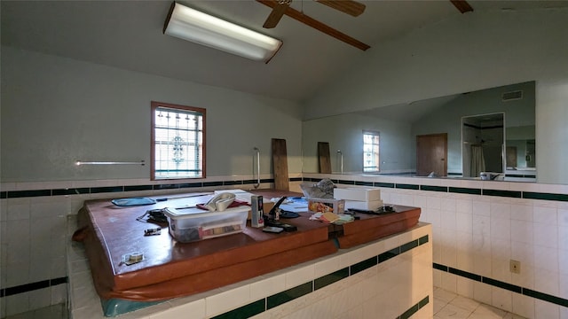 kitchen featuring light tile patterned flooring, lofted ceiling, plenty of natural light, and tile walls