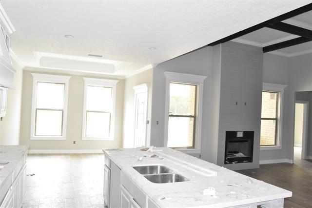 kitchen featuring crown molding, light stone countertops, an island with sink, and white cabinets