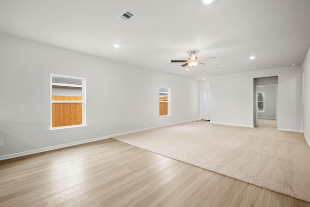 unfurnished room with a wealth of natural light, light hardwood / wood-style floors, and ceiling fan