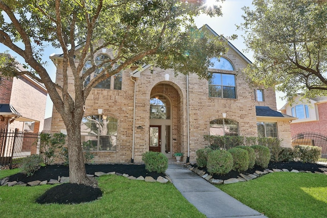 traditional-style home with fence, a front lawn, and brick siding