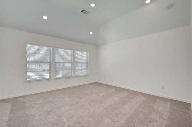 spare room with light carpet, baseboards, visible vents, and vaulted ceiling