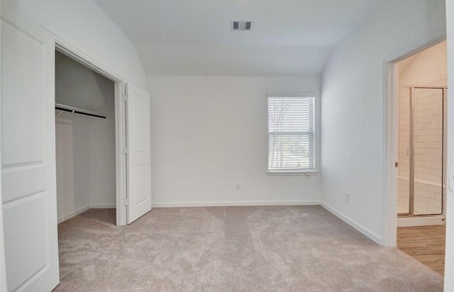 unfurnished bedroom featuring visible vents, carpet flooring, vaulted ceiling, ensuite bath, and baseboards