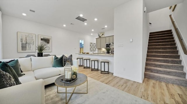 living area featuring recessed lighting, visible vents, stairway, and light wood finished floors