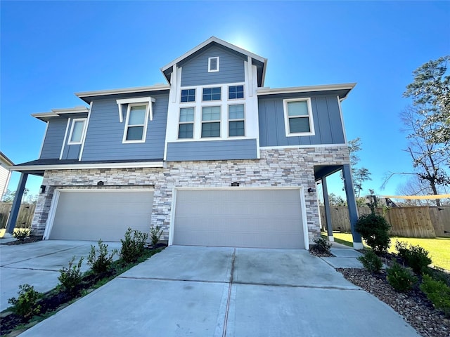 view of front of house featuring concrete driveway, board and batten siding, fence, a garage, and stone siding