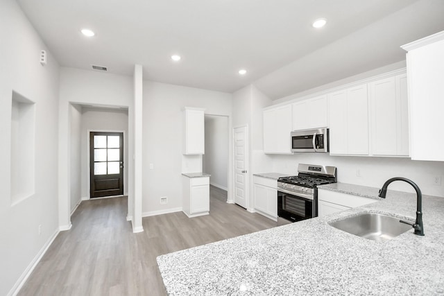 kitchen with light stone counters, sink, stainless steel appliances, and white cabinets