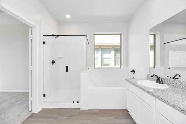 bathroom with a healthy amount of sunlight, separate shower and tub, and hardwood / wood-style floors