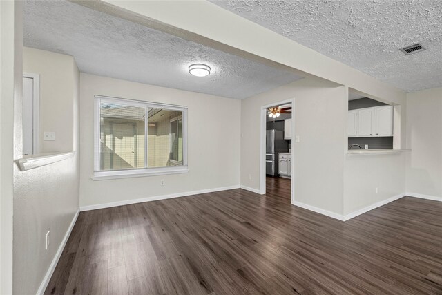 unfurnished living room with ceiling fan, a textured ceiling, and dark hardwood / wood-style flooring