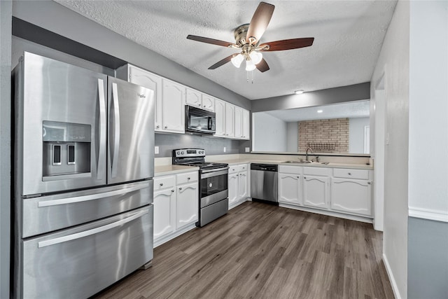 kitchen with stainless steel appliances, dark hardwood / wood-style floors, white cabinets, and a textured ceiling