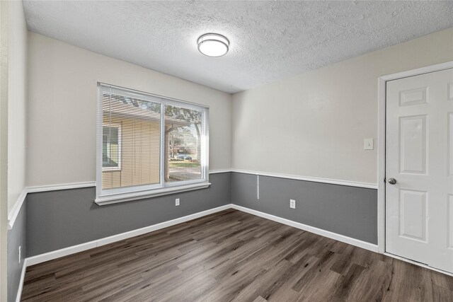 empty room with dark wood-type flooring and a textured ceiling