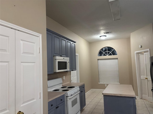 kitchen featuring light tile patterned floors, white appliances, gray cabinets, and a center island