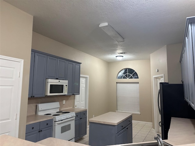 kitchen featuring gray cabinets, a kitchen island, light tile patterned floors, white appliances, and a textured ceiling