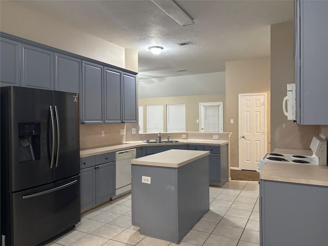 kitchen with sink, white appliances, a center island, light tile patterned flooring, and kitchen peninsula