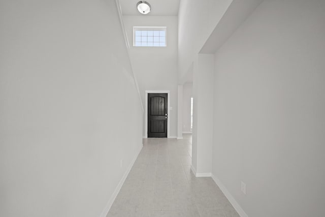 hallway with baseboards and a towering ceiling