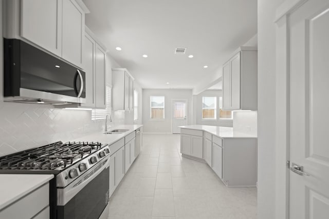 kitchen featuring visible vents, a sink, decorative backsplash, light countertops, and appliances with stainless steel finishes