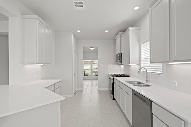 kitchen with visible vents, light countertops, decorative backsplash, appliances with stainless steel finishes, and a sink